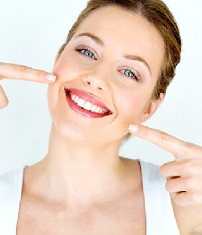 Woman pointing to flawless smile after dental bonding