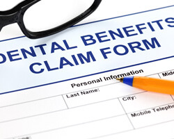 close-up of dental benefits claim form with pen and glasses