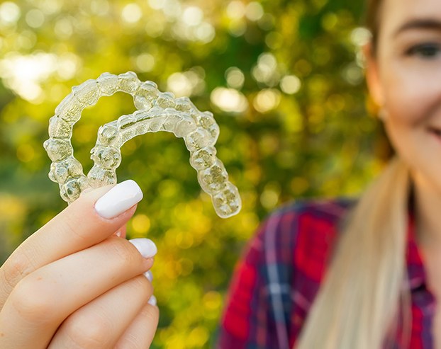 Female holding aligners for Invisalign Teen treatment in Boston