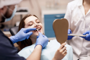 Woman smiling as dentist adheres a porcelain veneer to her tooth